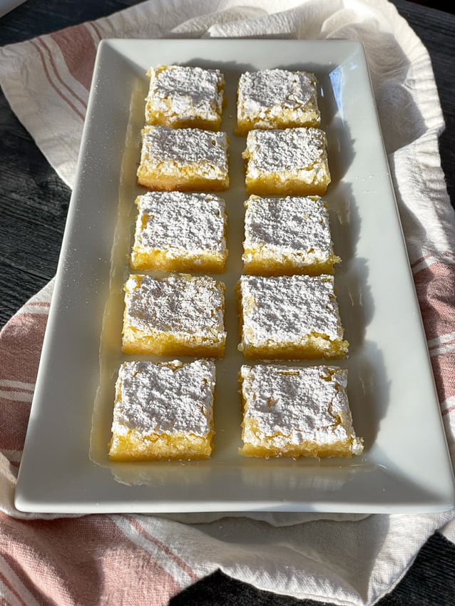A serving platter with lemon squares on it.