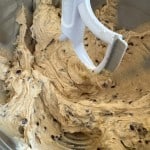 A mixing bowl with cookie dough and chocolate chips being mixed by a paddle attachment, ready to transform into scrumptious banana bars.