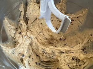 A mixing bowl with cookie dough and chocolate chips being mixed by a paddle attachment, ready to transform into scrumptious banana bars.