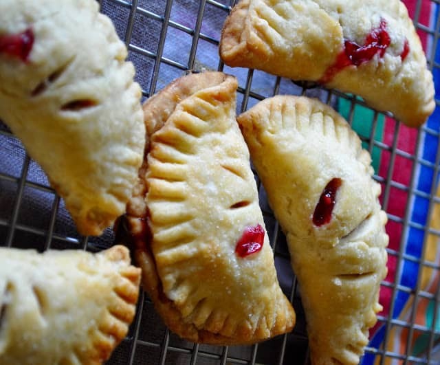 Mini hand pies with jam filling in a cooling rack.