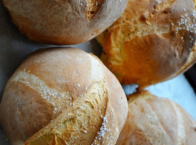 Freshly baked bread bowls sprinkled with kosher salt in a baking sheet.