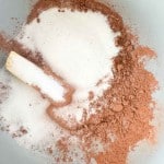 Sugar, cocoa powder, and a stick of butter in a gray mixing bowl, ready to be combined for delicious Texas Sheet Cake Cookies.