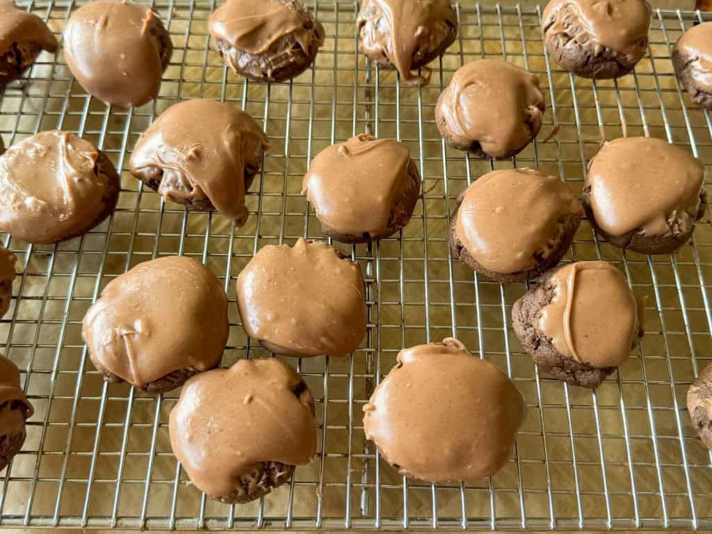 A cooling rack with rows of Texas Sheet Cake Cookies, each topped with a smooth chocolate glaze.