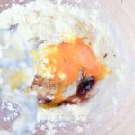 A glass mixing bowl containing creamed butter and sugar, with cracked eggs and vanilla extract added, ready to be mixed with an electric beater for delicious Texas Sheet Cake Cookies.