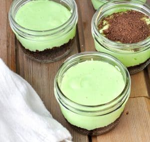 Jars of mint cheesecake with one topped with crushed grahams.