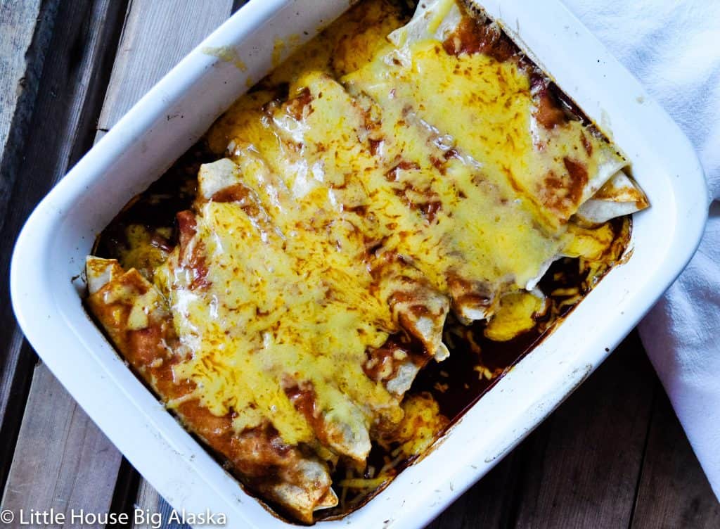 Beef and Bean smothered Burrito in a pan covered in sauce and cheese.