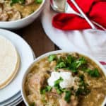 A table set with two bowls of Chile Verde and tortillas.