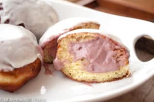 Homemade Lemon Doughnuts with Raspberry Cream cut in half with cream exposed.