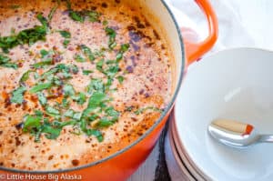 A pot of lasagna soup alongside serving bowls.