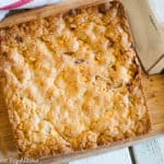 Full pan of butterscotch brownies on a chopping board with a knife on the side.