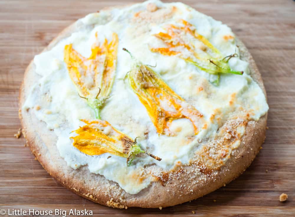 Focaccia bread spread with ricotta, topped with squash blossoms, sprinkled with Parmessan, and finished with kosher salt.  