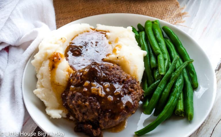 Salisbury steak served with mashed potatoes and green beans.