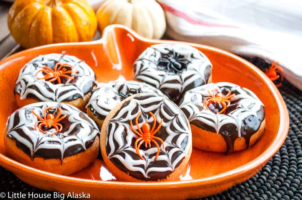 Doughnuts decorated with spider web designs and topped with spider ring.