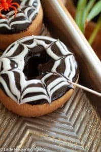 Designing a spider web on a donut using a toothpick.