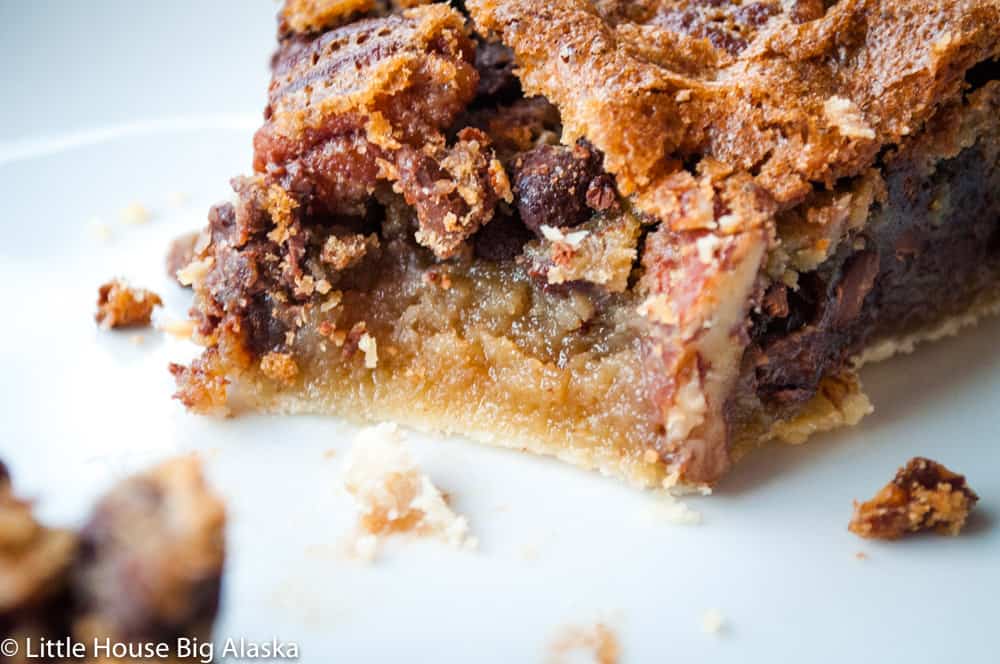 a slice of chocolate pecan pie with a bit take out of it 