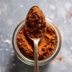 A jar of DIY taco seasoning with a spoonful scooped out.