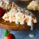 Strawberry scones drizzled with icing and a fresh strawberry on the sides.