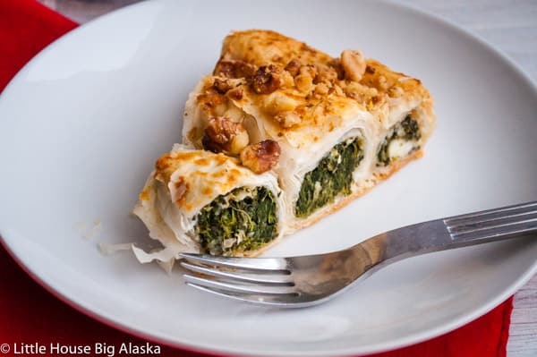 A slice of GBBO spanakopita spiral pie on a plate, showcasing its flaky layers.