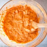 Kimchi pancake batter mixed in a bowl with a wooden spoon.
