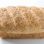 A loaf of whole grain spelt bread with flax and sesame seeds.
