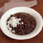A bowl of black bean soup garnished with diced garlic.