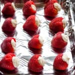 Strawberries filled with cheesecake in a foiled pan.