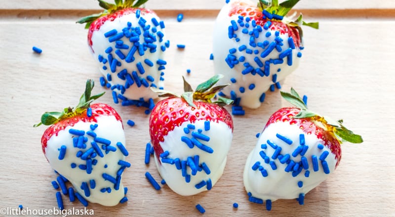 Strawberries dipped in white chocolate and sprinkled with blue sprinkles.