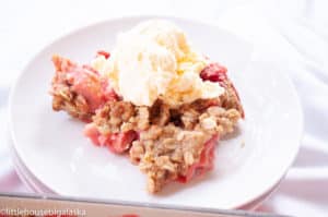Strawberry rhubarb crisp topped with vanilla ice cream.