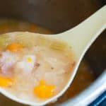 A ladle full of navy bean with bacon soup.