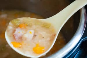 A ladle full of navy bean with bacon soup.