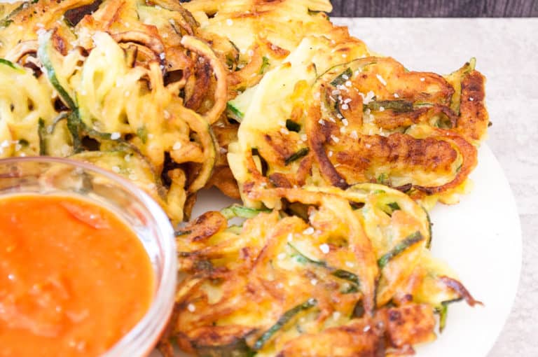 Zucchini pancakes sprinkled with salt with sauce on the side.