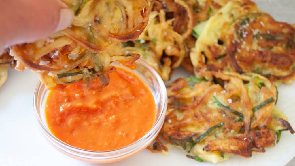 Zucchini pancakes sprinkled with salt dipped into the sauce.