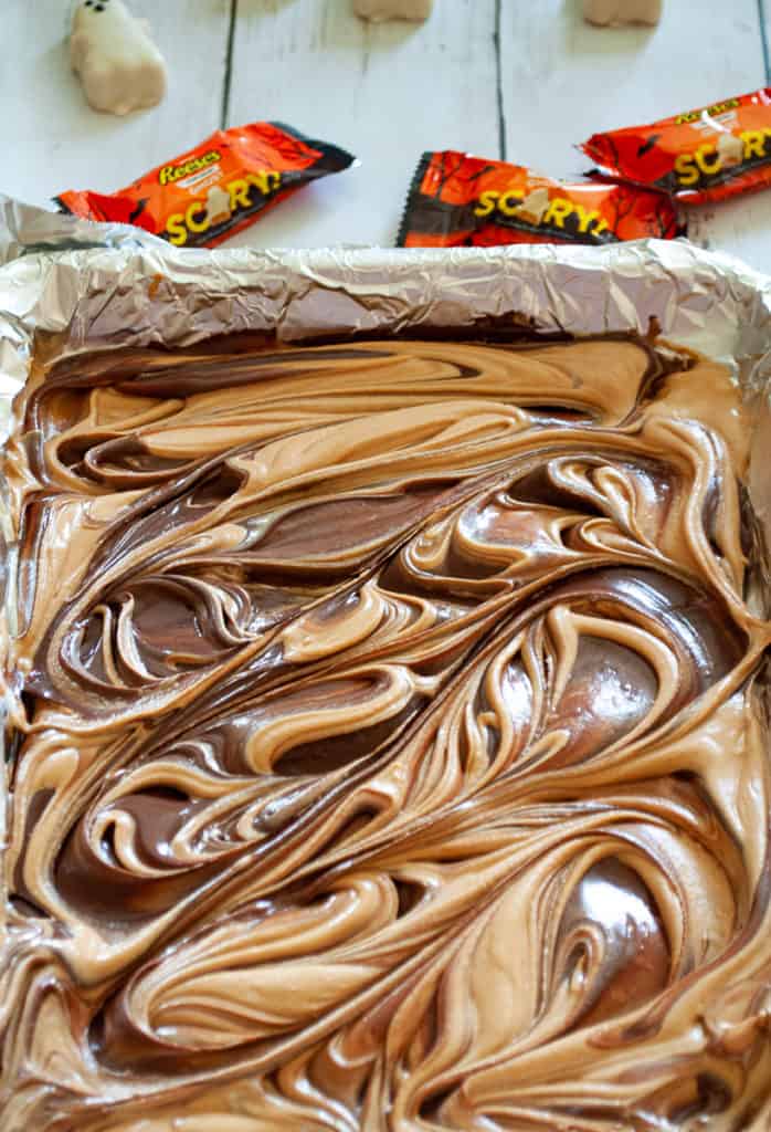 Swirled melted chocolate and peanut buutter chips on a baking tray