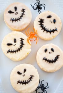 Five Jack Skellington-themed Halloween cookies arranged on a white plate.