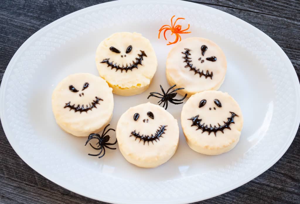 Five Jack Skellington-themed Halloween cookies arranged on a white plate.
