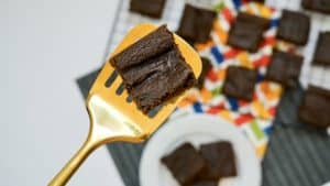 A slice if pumpkin brownie in a golden spatula with the rest of it in the background.