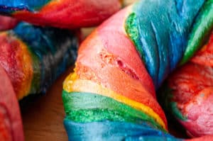 Close-up photo of a rainbow bagel, highlighting its vibrant swirl of colors and texture.