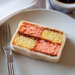 A slice of Battenberg cake showing it's pink and yellow checker board pattern.