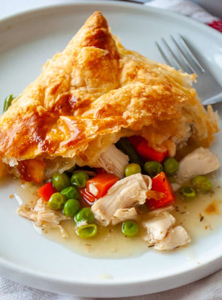 A slice of savory turkey pot pie with a golden and flaky puff pastry crust.