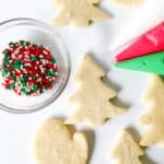 Christmas sugar cookie decorating setup with undecorated, no spread sugar cookies and colorful sprinkles.