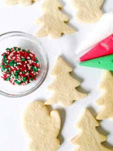Christmas sugar cookie decorating setup with undecorated, no spread sugar cookies and colorful sprinkles.