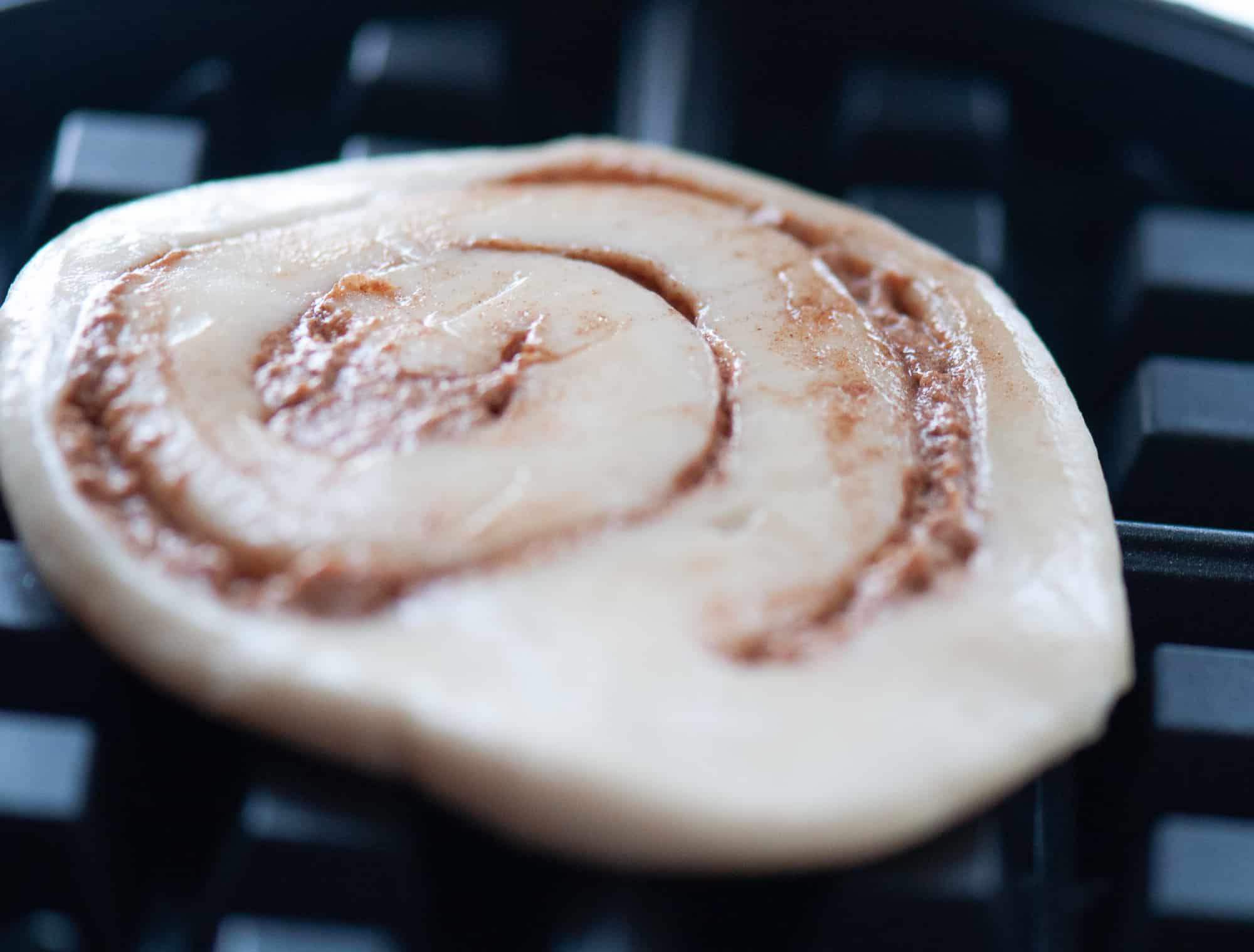 A cinnamon roll in the waffle maker.