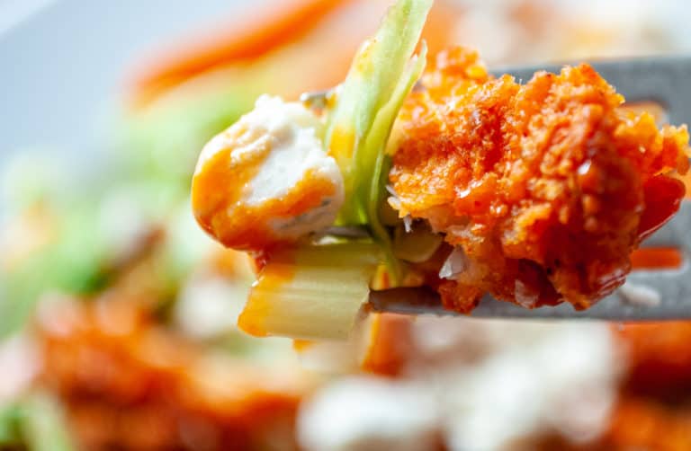 Buffalo chicken salad on a fork with celery and dipping sauce.