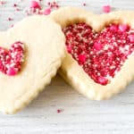 Heart-shaped Red Velvet Sugar Cookies decorated with pink and red sprinkles.