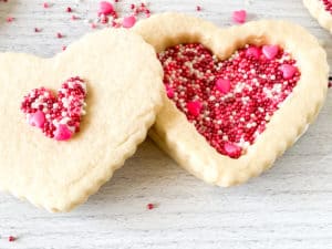 Heart-shaped Red Velvet Sugar Cookies decorated with pink and red sprinkles.