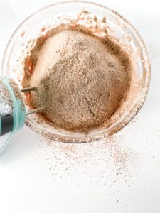 A mixing bowl with blended dry ingredients for Red Velvet Sugar Cookies, with a hand mixer off to the side.