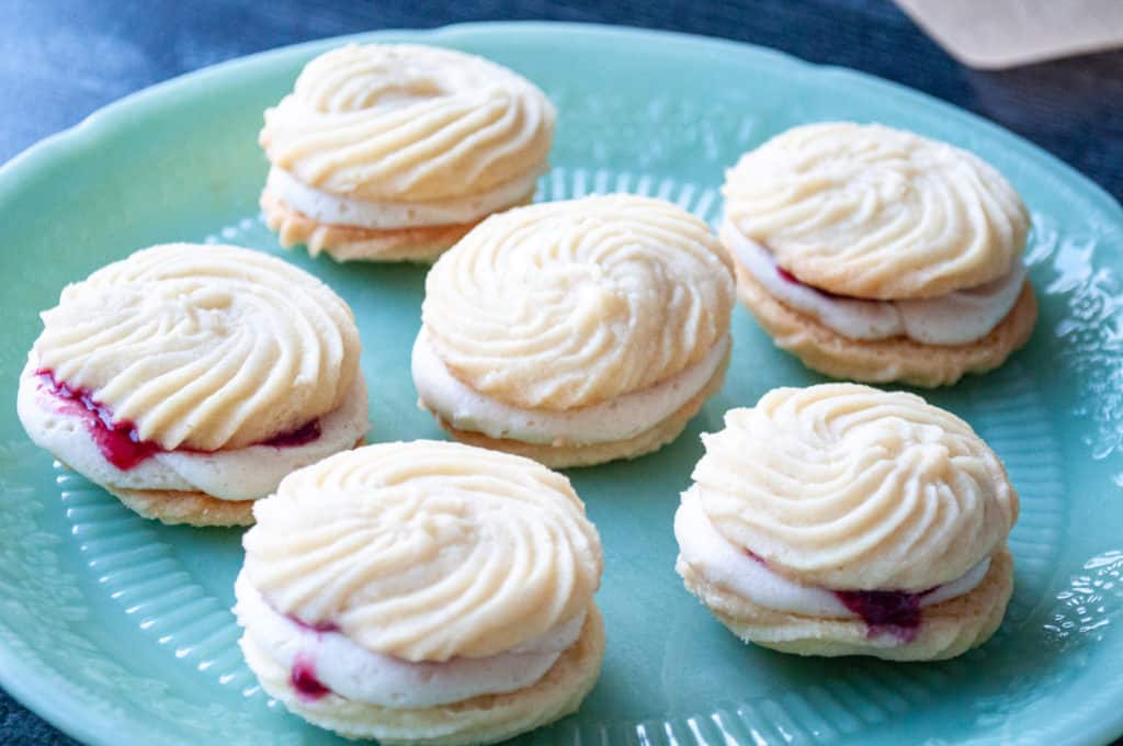 A plate of freshly baked Viennese Whirls sandwich cookies with jam filling.
