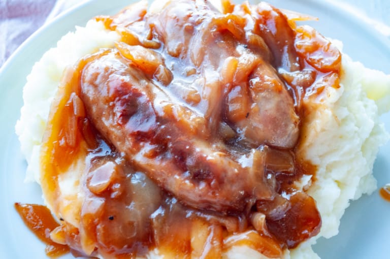 Plate of Easy Bangers and Mash topped with onion gravy.