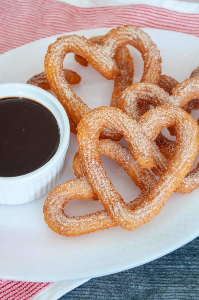 Plate with chocolate dipping sauce and heart shaped churros.