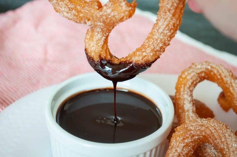 Dipping a churros in chocolate sauce.